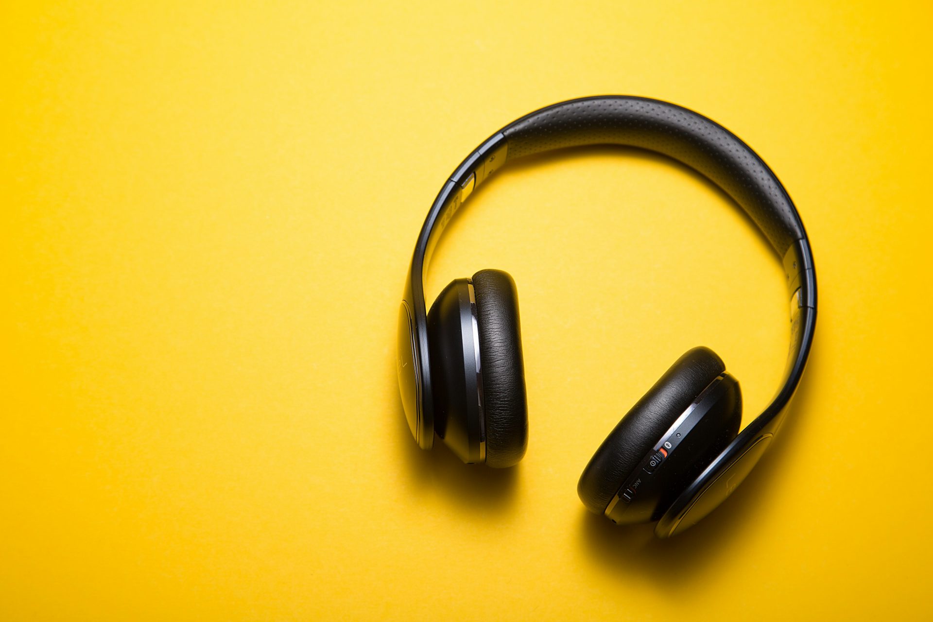 Black headphones on a bright yellow background.
